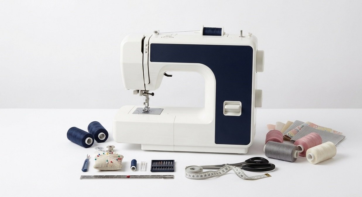 Beginner sewing machine with essential sewing tools, thread spools, scissors, measuring tape, needles and pincushion